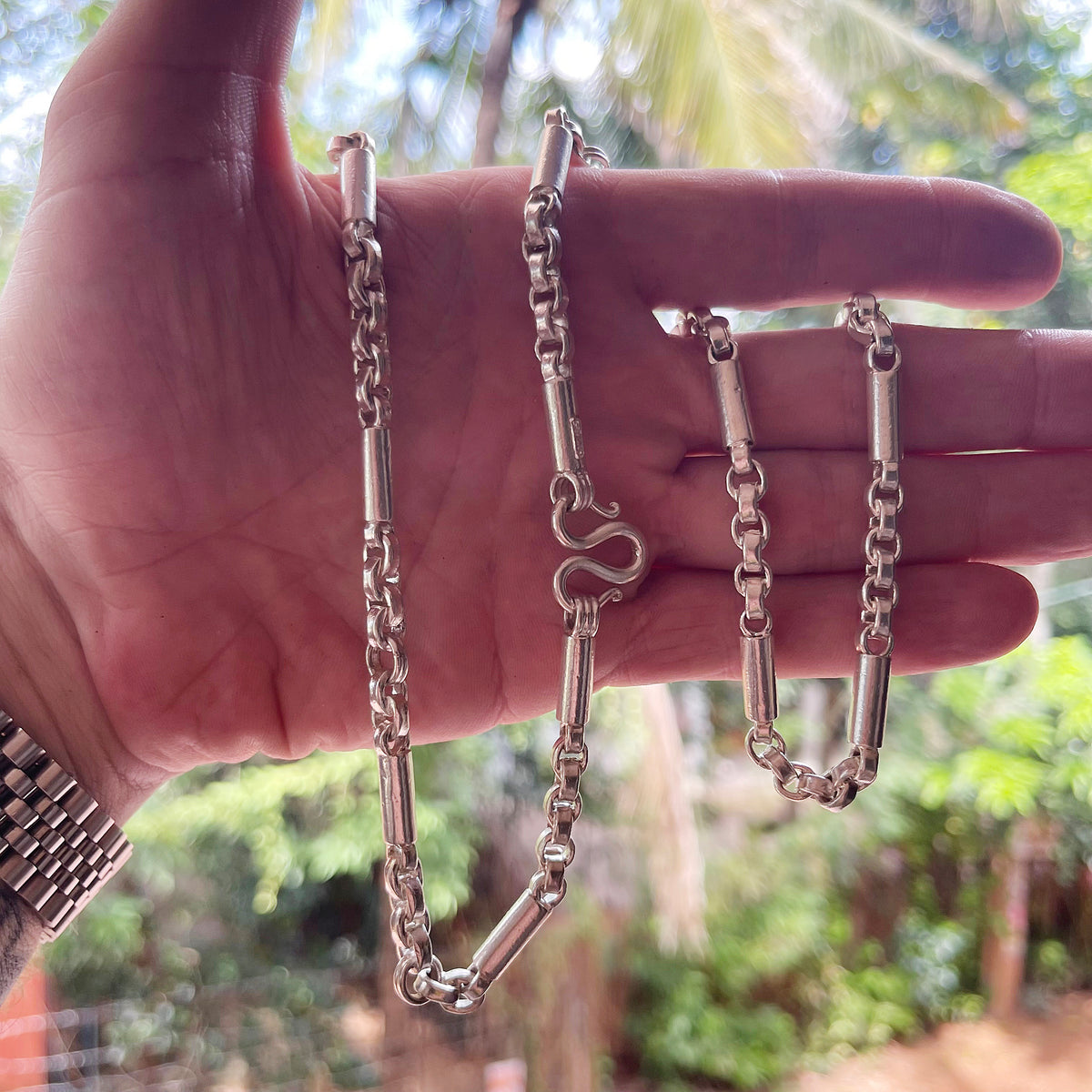 Hand holding round figaro belcher mens-silver-necklace. DEXZION
